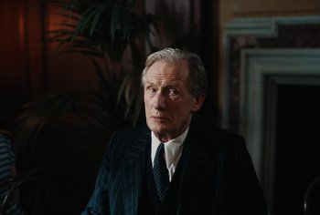 Movie still from “Living” (2022), directed by Oliver Hermanus – An older man wearing a suit and tie; Close Up shot, Low angle