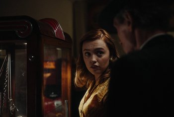 Movie still from “Living” (2022), directed by Oliver Hermanus – A woman standing next to a man in front of a display case; Medium shot, Over the shoulder angle