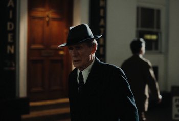 Movie still from “Living” (2022), directed by Oliver Hermanus – An older man in a suit and hat walking; Medium shot, Low angle