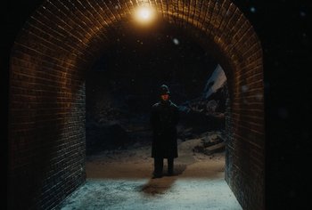 Movie still from “Living” (2022), directed by Oliver Hermanus – A man standing in a tunnel with snow on the ground; Wide shot, Over the shoulder angle