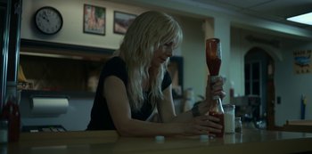 Movie still from “Lost Girls” (2020), directed by Liz Garbus – A woman is holding up a bottle of ketchup; Medium shot, High angle