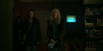 Movie still from “Lost Girls” (2020), directed by Liz Garbus – Two women standing in front of a television in a living room; Medium shot, Low angle