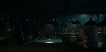 Movie still from “Lost Girls” (2020), directed by Liz Garbus – A group of people playing a game of billiards; Wide shot, High angle