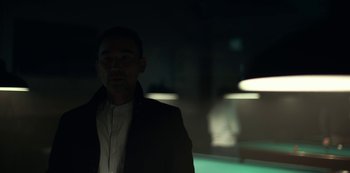 Movie still from “Lost Girls” (2020), directed by Liz Garbus – A man standing in a dark room with lights in the background; Close Up shot, Low angle