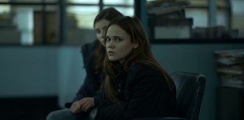 Movie still from “Lost Girls” (2020), directed by Liz Garbus – Two young women sitting on a couch in a dark room; Close Up shot, Over the shoulder angle
