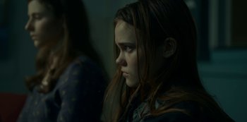 Movie still from “Lost Girls” (2020), directed by Liz Garbus – A young girl with long brown hair stares into the distance; Close Up shot, Over the shoulder angle
