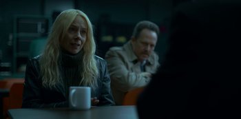 Movie still from “Lost Girls” (2020), directed by Liz Garbus – A woman sitting at a table with a cup of coffee in front of a man; Medium shot, Over the shoulder angle