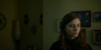 Movie still from “Lost Girls” (2020), directed by Liz Garbus – A young girl in a black shirt is looking to her left; Close Up shot, High angle
