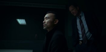 Movie still from “Lost Girls” (2020), directed by Liz Garbus – A man in a suit and tie standing next to another man in a suit and tie; Medium shot, Low angle