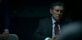 Movie still from “Lost Girls” (2020), directed by Liz Garbus – An older man in a suit and red tie; Close Up shot, Low angle