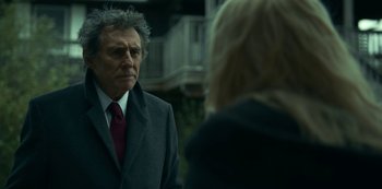 Movie still from “Lost Girls” (2020), directed by Liz Garbus – A man wearing a suit and tie standing next to a woman wearing a jacket; Close Up shot, Over the shoulder angle