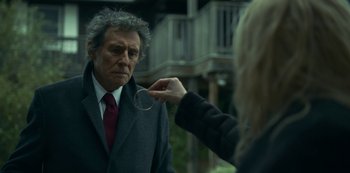 An older man wearing a suit and red tie looking at a young woman
