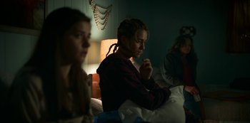 Movie still from “Lost Girls” (2020), directed by Liz Garbus – A group of people sitting in a room; Medium shot, Low angle