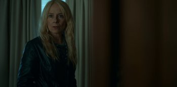 Movie still from “Lost Girls” (2020), directed by Liz Garbus – A woman with long blonde hair standing in front of a window; Close Up shot, Over the shoulder angle