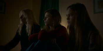 Movie still from “Lost Girls” (2020), directed by Liz Garbus – A group of people sitting in a room; Medium shot, Low angle