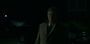 Movie still from “Lost Girls” (2020), directed by Liz Garbus – An older man wearing a suit and tie in the dark; Close Up shot, Over the shoulder angle