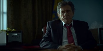 Movie still from “Lost Girls” (2020), directed by Liz Garbus – A man in a suit and tie sitting at a table; Close Up shot, Over the shoulder angle