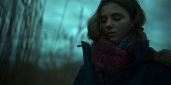Movie still from “Lost Girls” (2020), directed by Liz Garbus – A woman in a jacket and a scarf is standing in the rain; Close Up shot, Low angle