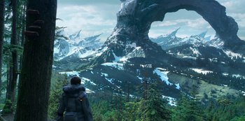 Movie still from “Lost in Space” (2018), created by Irwin Allen – A man standing in front of a large mountain; Extreme Wide shot, High angle