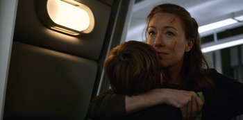 Movie still from “Lost in Space” (2018), created by Irwin Allen – A woman hugging a man on a plane; Close Up shot, Low angle