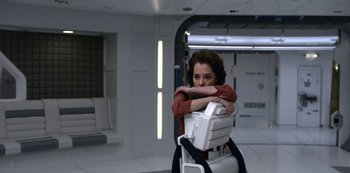 Movie still from “Lost in Space” (2018), created by Irwin Allen – A woman leaning on a computer chair in a room; Medium shot, High angle