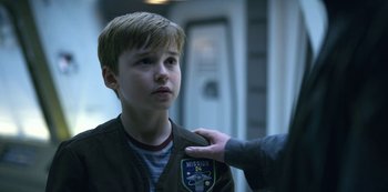 Movie still from “Lost in Space” (2018), created by Irwin Allen – A young boy is being given a medal by an older man; Close Up shot, Over the shoulder angle
