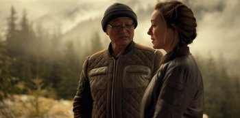 Movie still from “Lost in Space” (2018), created by Irwin Allen – An older man and a younger woman standing next to each other in a wooded area; Close Up shot, Over the shoulder angle