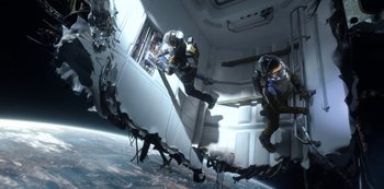 Movie still from “Lost in Space” (2018), created by Irwin Allen – Two people in space suits in an enclosed space; Wide shot, Overhead angle