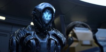 Movie still from “Lost in Space” (2018), created by Irwin Allen – A man in a futuristic suit with a glowing face; Medium shot, Over the shoulder angle