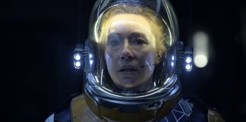 Movie still from “Lost in Space” (2018), created by Irwin Allen – A woman wearing a space helmet in the dark; Close Up shot, Over the shoulder angle