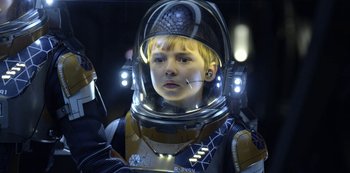 Movie still from “Lost in Space” (2018), created by Irwin Allen – A young boy in a space suit with lights on; Close Up shot, Over the shoulder angle