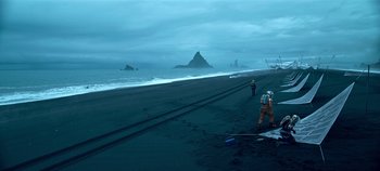 Movie still from “Lost in Space” (2018), created by Irwin Allen – Two people standing on a beach near the ocean; Extreme Wide shot, High angle