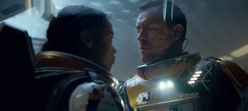 Movie still from “Lost in Space” (2018), created by Irwin Allen – A man standing next to a woman in front of a building; Close Up shot, Over the shoulder angle