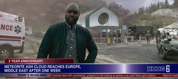 Movie still from “Lost in Space” (2018), created by Irwin Allen – A man standing in front of a building with smoke billowing out of it; Medium shot, Over the shoulder angle