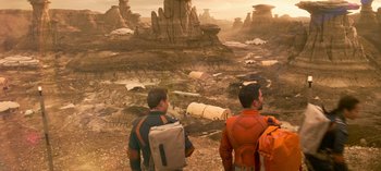 Movie still from “Lost in Space” (2018), created by Irwin Allen – Two men are standing in an alien landscape; Extreme Wide shot, High angle
