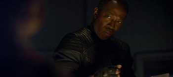 Movie still from “Lost in Space” (2018), created by Irwin Allen – A man holding a game controller in a dark room; Close Up shot, Over the shoulder angle