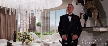 Movie still from “Indiana Jones and the Last Crusade” (1989), directed by Steven Spielberg – A man in a tuxedo holding a glass of wine; Medium shot, Low angle