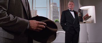 Movie still from “Indiana Jones and the Last Crusade” (1989), directed by Steven Spielberg – A man in a tuxedo is looking at another man in a hat; Medium shot, Over the shoulder angle