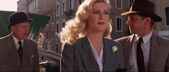 Movie still from “Indiana Jones and the Last Crusade” (1989), directed by Steven Spielberg – A woman with blonde hair wearing a gray suit and red lipstick; Medium shot, Low angle