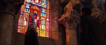 Movie still from “Indiana Jones and the Last Crusade” (1989), directed by Steven Spielberg – A woman standing in front of a stained - glass window; Wide shot, Low angle