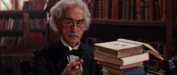Movie still from “Indiana Jones and the Last Crusade” (1989), directed by Steven Spielberg – An old man in a suit smoking a pipe and holding an apple; Close Up shot, Low angle