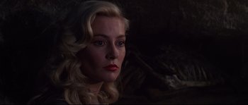 Movie still from “Indiana Jones and the Last Crusade” (1989), directed by Steven Spielberg – A woman with blonde hair and red lipstick looking to her left; Close Up shot, Over the shoulder angle