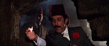 Movie still from “Indiana Jones and the Last Crusade” (1989), directed by Steven Spielberg – A man with a fez and a cigarette in his mouth; Medium shot, Low angle