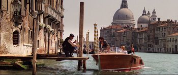 Movie still from “Indiana Jones and the Last Crusade” (1989), directed by Steven Spielberg – Two men are standing on a pier near a boat in the water; Wide shot, High angle