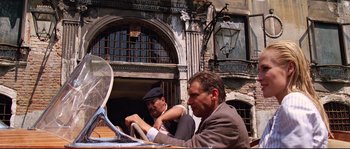 Movie still from “Indiana Jones and the Last Crusade” (1989), directed by Steven Spielberg – A couple of men sitting at a table in front of a building; Wide shot, Low angle