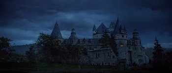 Movie still from “Indiana Jones and the Last Crusade” (1989), directed by Steven Spielberg – A castle like building in the dark with a cloudy sky above it; Extreme Wide shot, Low angle