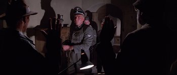 Movie still from “Indiana Jones and the Last Crusade” (1989), directed by Steven Spielberg – A man in a military uniform is holding a flashlight; Medium shot, Low angle