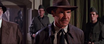 Movie still from “Indiana Jones and the Last Crusade” (1989), directed by Steven Spielberg – A person wearing a suit and tie; Close Up shot, Over the shoulder angle