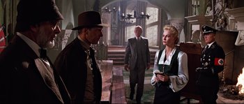 Movie still from “Indiana Jones and the Last Crusade” (1989), directed by Steven Spielberg – A group of people standing around in a room; Wide shot, Low angle