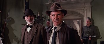 Movie still from “Indiana Jones and the Last Crusade” (1989), directed by Steven Spielberg – A person wearing a suit and tie; Medium shot, Low angle